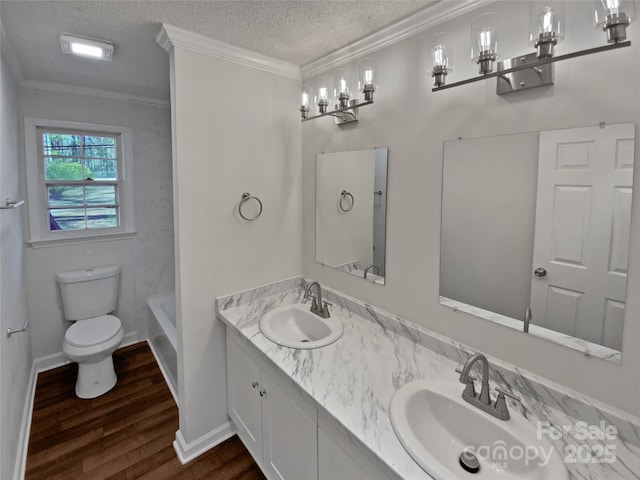 bathroom with a textured ceiling, wood-type flooring, vanity, toilet, and crown molding