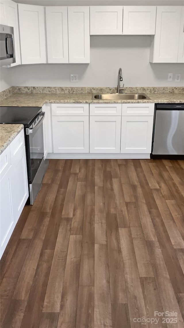 kitchen with sink, white cabinets, dark wood-type flooring, and appliances with stainless steel finishes