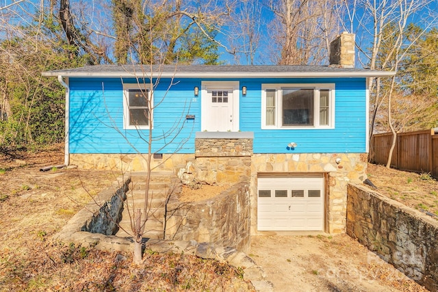 ranch-style home featuring a chimney, an attached garage, crawl space, fence, and stone siding