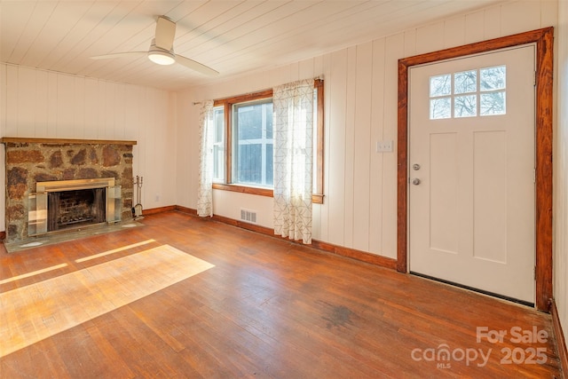 unfurnished living room featuring baseboards, visible vents, a ceiling fan, hardwood / wood-style floors, and a fireplace