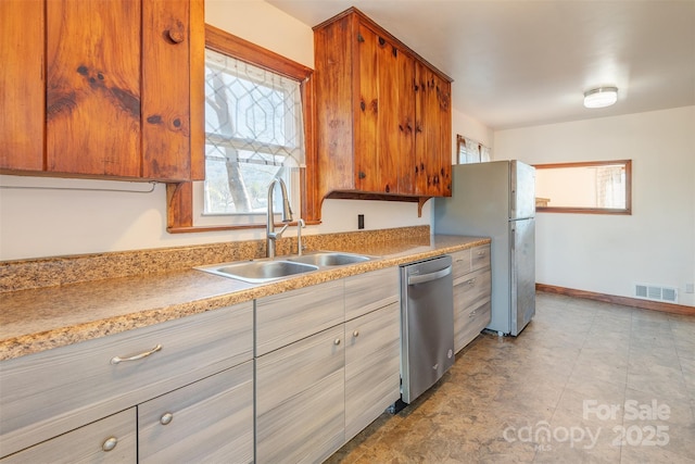 kitchen featuring visible vents, brown cabinets, stainless steel appliances, light countertops, and a sink