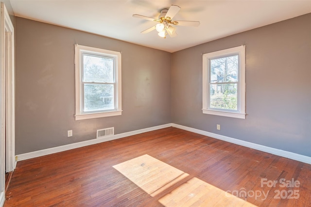 empty room featuring ceiling fan, wood finished floors, visible vents, and baseboards