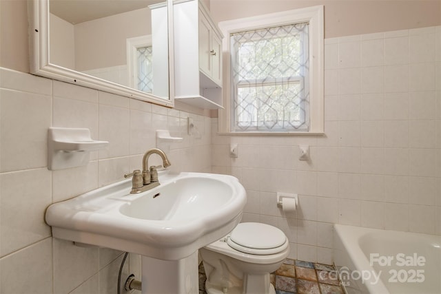 full bath with a tub, tile walls, and toilet