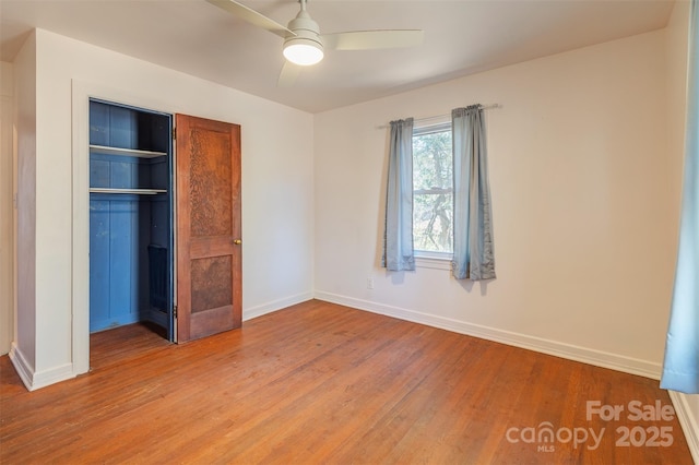 unfurnished bedroom featuring a ceiling fan, a closet, baseboards, and wood finished floors