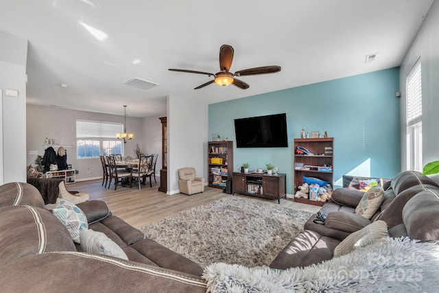 living room with ceiling fan with notable chandelier and light wood-type flooring