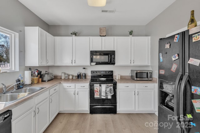 kitchen with white cabinetry, sink, light hardwood / wood-style flooring, and black appliances