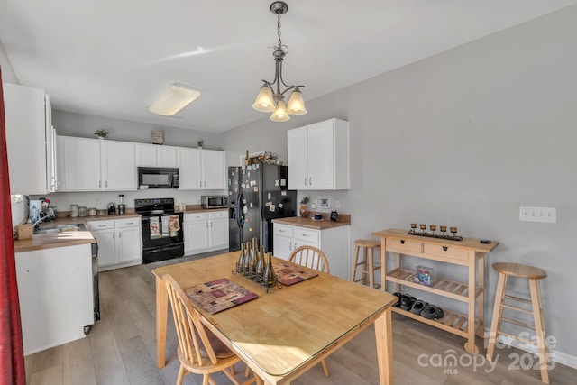 kitchen with pendant lighting, an inviting chandelier, black appliances, white cabinets, and light wood-type flooring