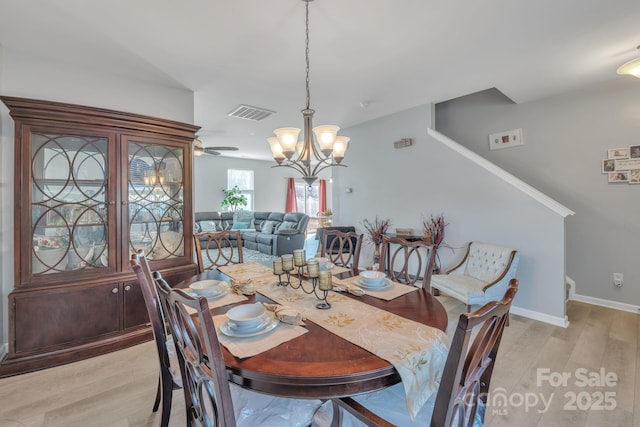 dining space featuring ceiling fan with notable chandelier and light wood-type flooring