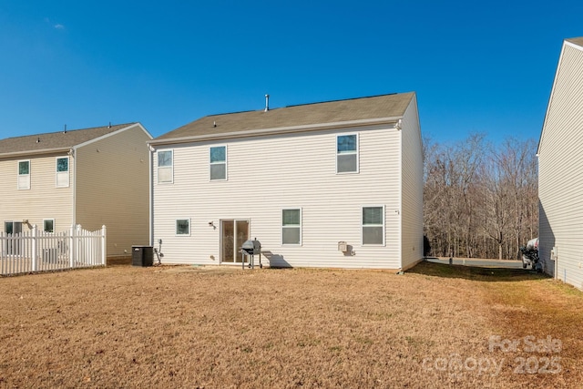 rear view of property with central AC and a yard