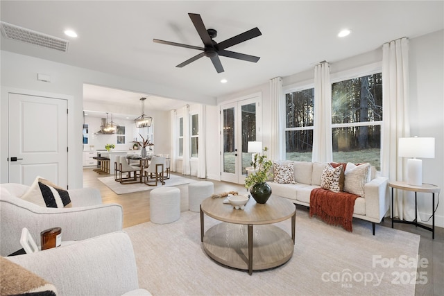 living room featuring ceiling fan with notable chandelier and light hardwood / wood-style floors