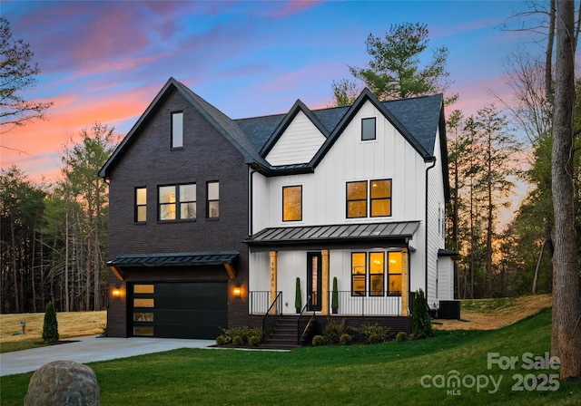 modern inspired farmhouse featuring a front yard, covered porch, metal roof, driveway, and a standing seam roof