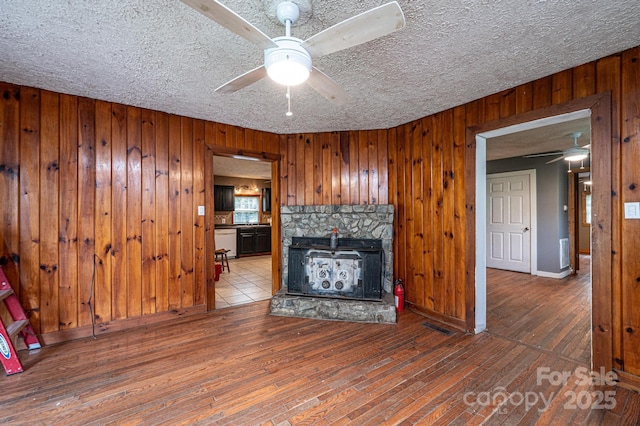 unfurnished living room featuring ceiling fan, wood walls, and hardwood / wood-style flooring