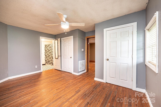 unfurnished bedroom with ceiling fan, dark wood-type flooring, and a textured ceiling