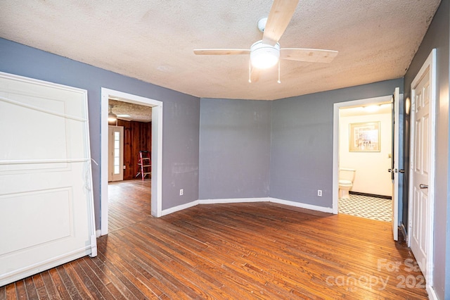 unfurnished bedroom featuring ceiling fan, ensuite bathroom, dark hardwood / wood-style flooring, and a textured ceiling