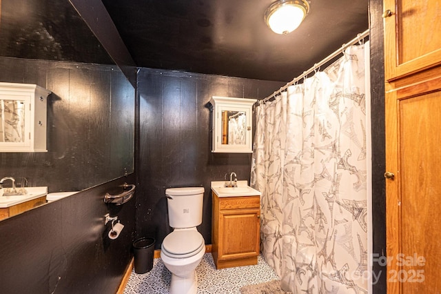 bathroom featuring toilet, vanity, and wood walls