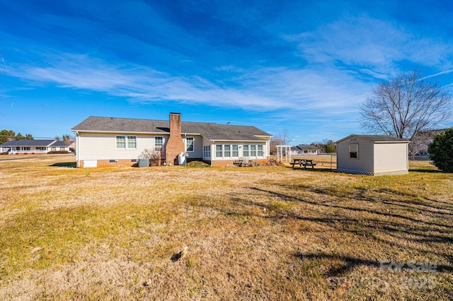 back of house featuring a yard and a storage shed