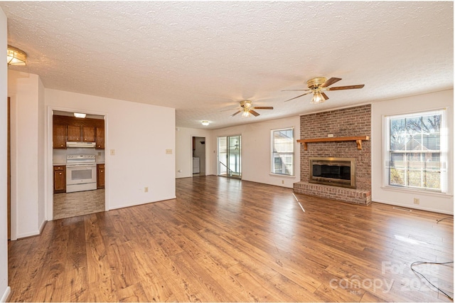 unfurnished living room featuring a fireplace, a textured ceiling, and light wood-type flooring