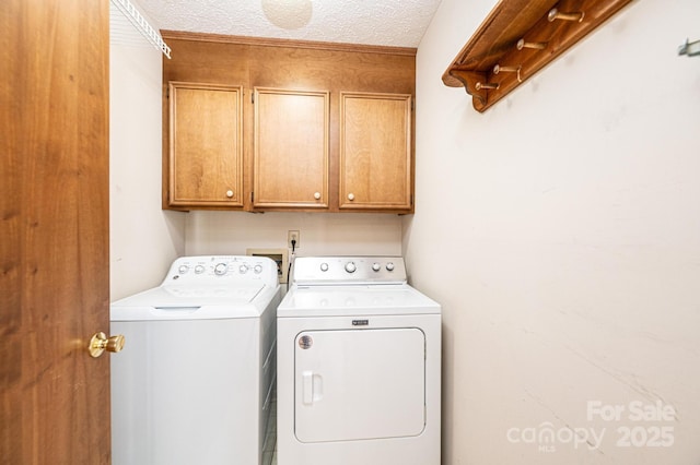 laundry room with independent washer and dryer, cabinets, and a textured ceiling