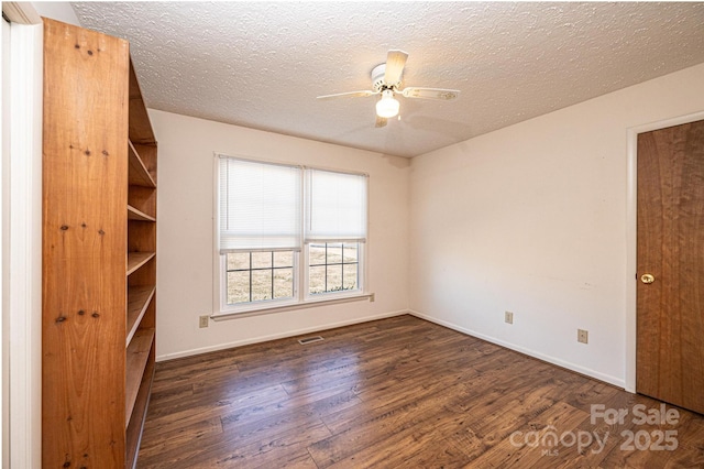 spare room featuring ceiling fan, dark hardwood / wood-style floors, and a textured ceiling