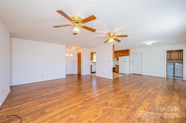 unfurnished living room with hardwood / wood-style flooring, washing machine and clothes dryer, ceiling fan, and a textured ceiling