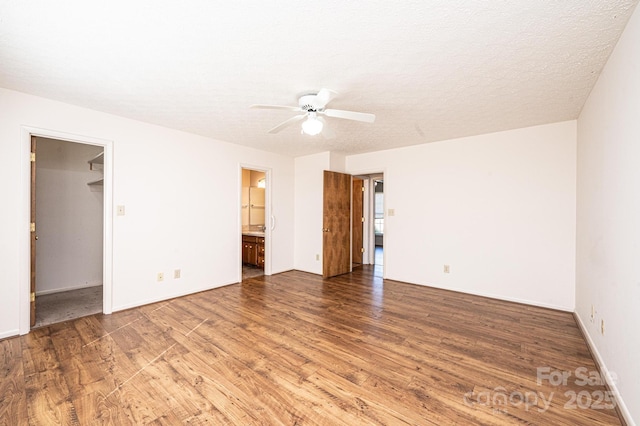 empty room with ceiling fan, wood-type flooring, and a textured ceiling