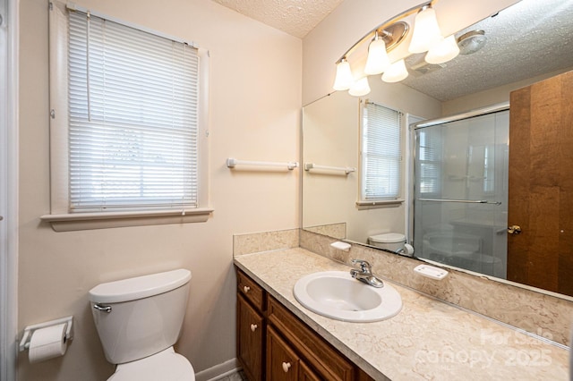 bathroom with toilet, vanity, a textured ceiling, and a shower with shower door