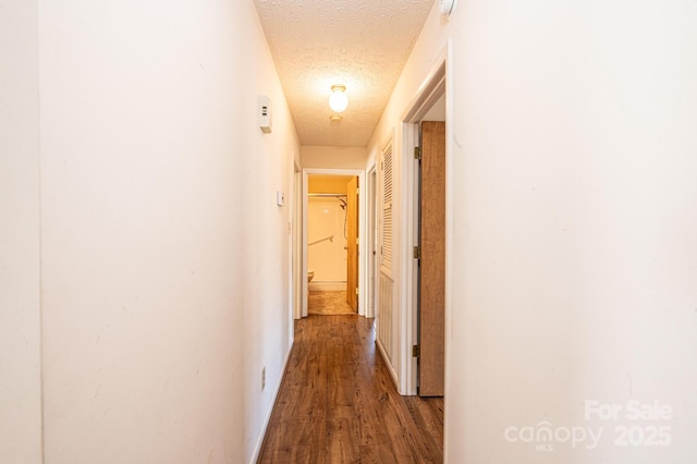 corridor with dark hardwood / wood-style flooring and a textured ceiling