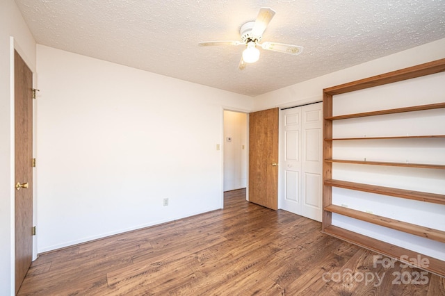 unfurnished bedroom with wood-type flooring, ceiling fan, a textured ceiling, and a closet