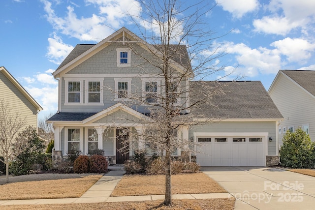 craftsman inspired home with a garage, driveway, a shingled roof, and stone siding