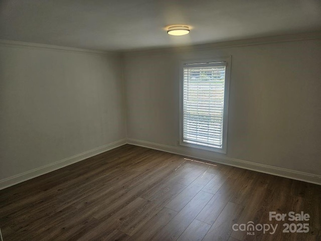 spare room featuring dark wood-type flooring and crown molding