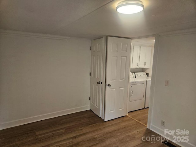 washroom with ornamental molding, hardwood / wood-style floors, cabinets, and washing machine and clothes dryer