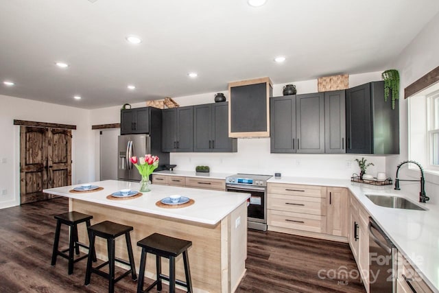 kitchen with appliances with stainless steel finishes, a center island, sink, dark hardwood / wood-style floors, and a breakfast bar area