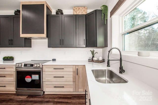 kitchen with light brown cabinets, electric stove, dark wood-type flooring, wall chimney range hood, and sink