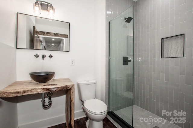 bathroom featuring sink, toilet, and a tile shower