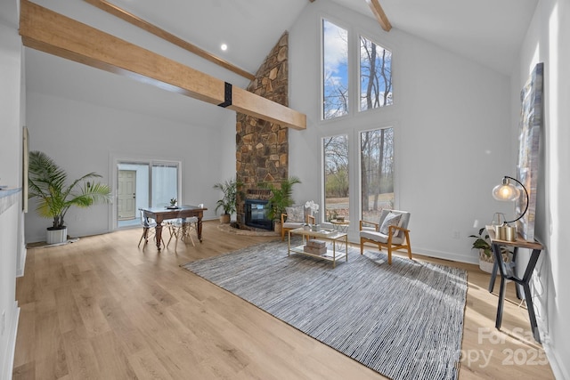 sitting room featuring light hardwood / wood-style flooring, beam ceiling, a fireplace, and a wealth of natural light