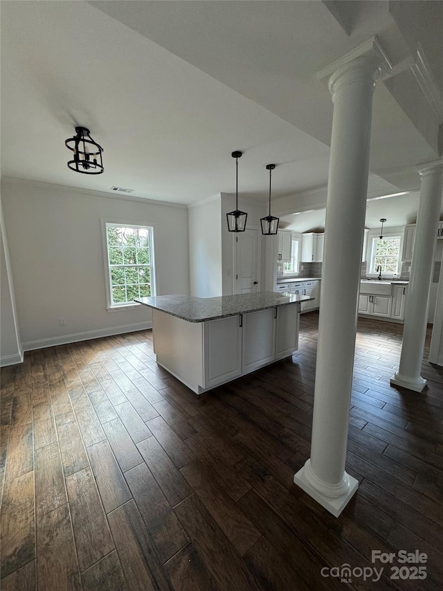 kitchen featuring decorative columns, dark wood-type flooring, white cabinetry, and a kitchen island