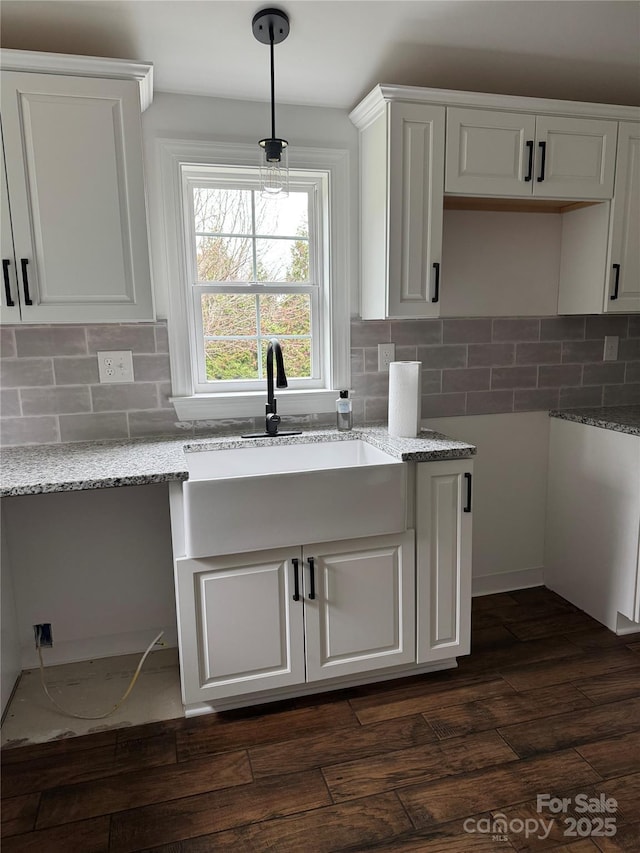 kitchen featuring white cabinetry, light stone counters, and sink