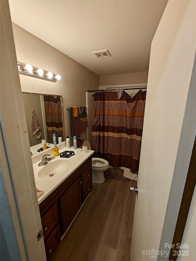 bathroom featuring hardwood / wood-style floors, a shower with shower curtain, vanity, a textured ceiling, and toilet