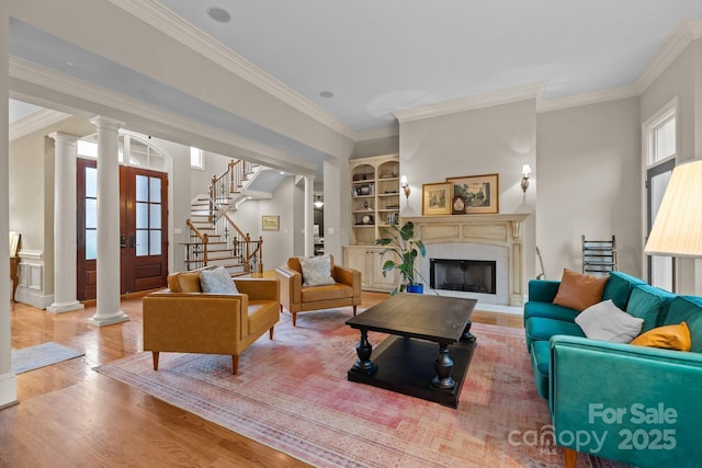 living area featuring a wealth of natural light, decorative columns, and stairway