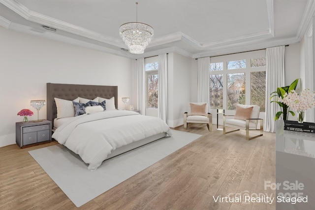 bedroom featuring ornamental molding, light wood-type flooring, a raised ceiling, and a chandelier