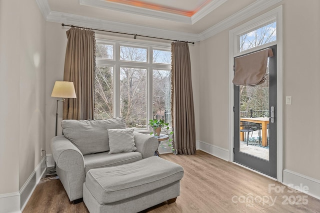 sitting room with a raised ceiling, crown molding, baseboards, and wood finished floors