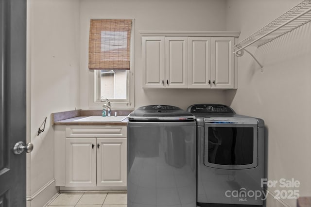 clothes washing area with cabinet space, light tile patterned flooring, a sink, and washing machine and clothes dryer