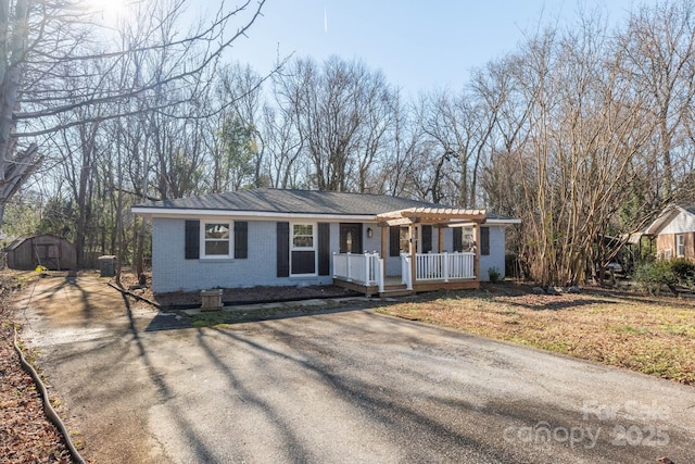 ranch-style home with a pergola, a porch, and a shed