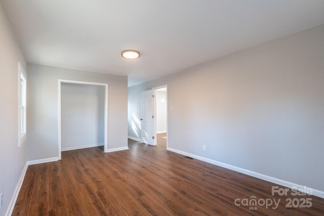 unfurnished bedroom featuring a closet and dark wood-type flooring