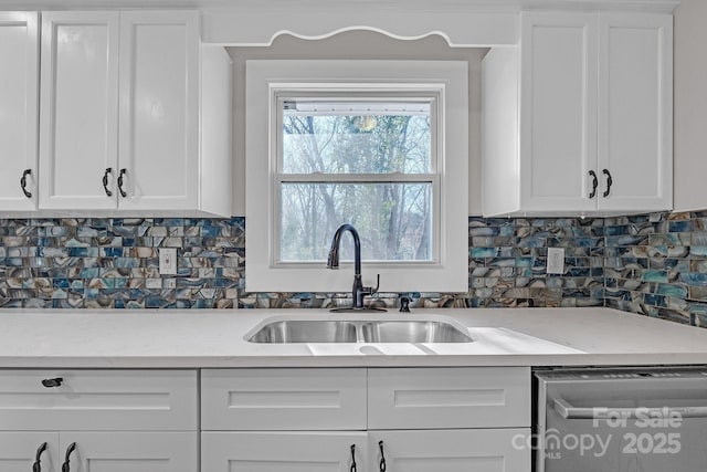 kitchen featuring sink, backsplash, stainless steel dishwasher, and white cabinets