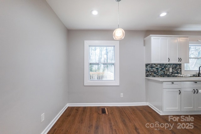 kitchen featuring pendant lighting, white cabinets, dark hardwood / wood-style floors, and tasteful backsplash