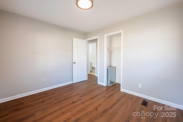 unfurnished bedroom with a closet and dark hardwood / wood-style flooring