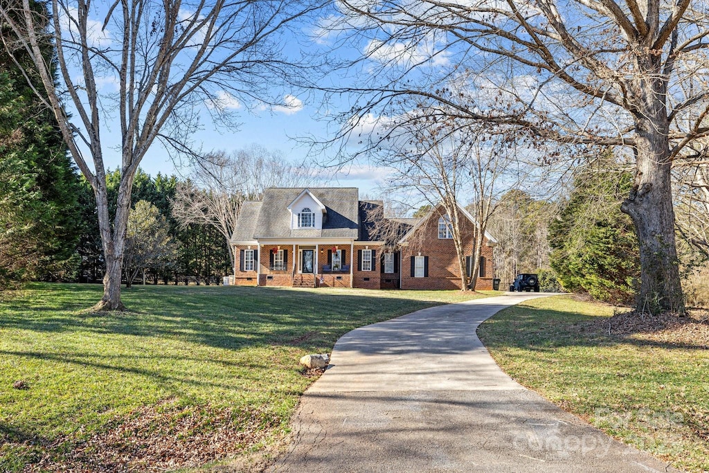 new england style home featuring a front lawn and covered porch