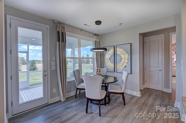 dining space featuring baseboards, visible vents, a wealth of natural light, and wood finished floors