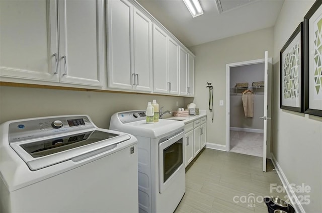 laundry area with washer and clothes dryer, a sink, cabinet space, and baseboards